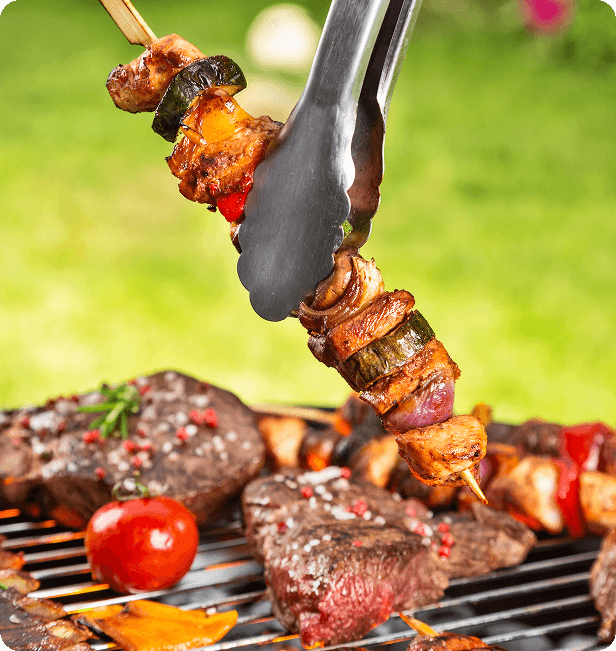A chef grills kabobs in a backyard