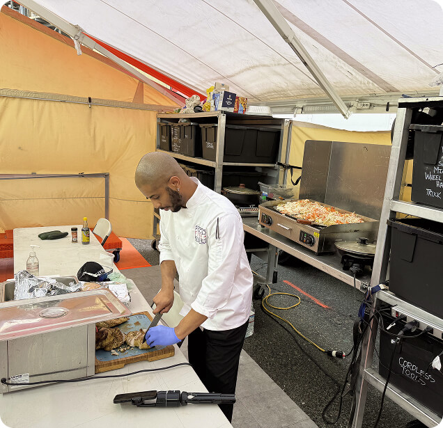A chef preparing meals in a racing paddock.